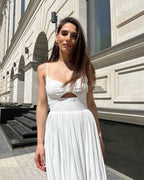 Rochie alba elegantă midi cu bretele și slit, accesorizată cu centură.