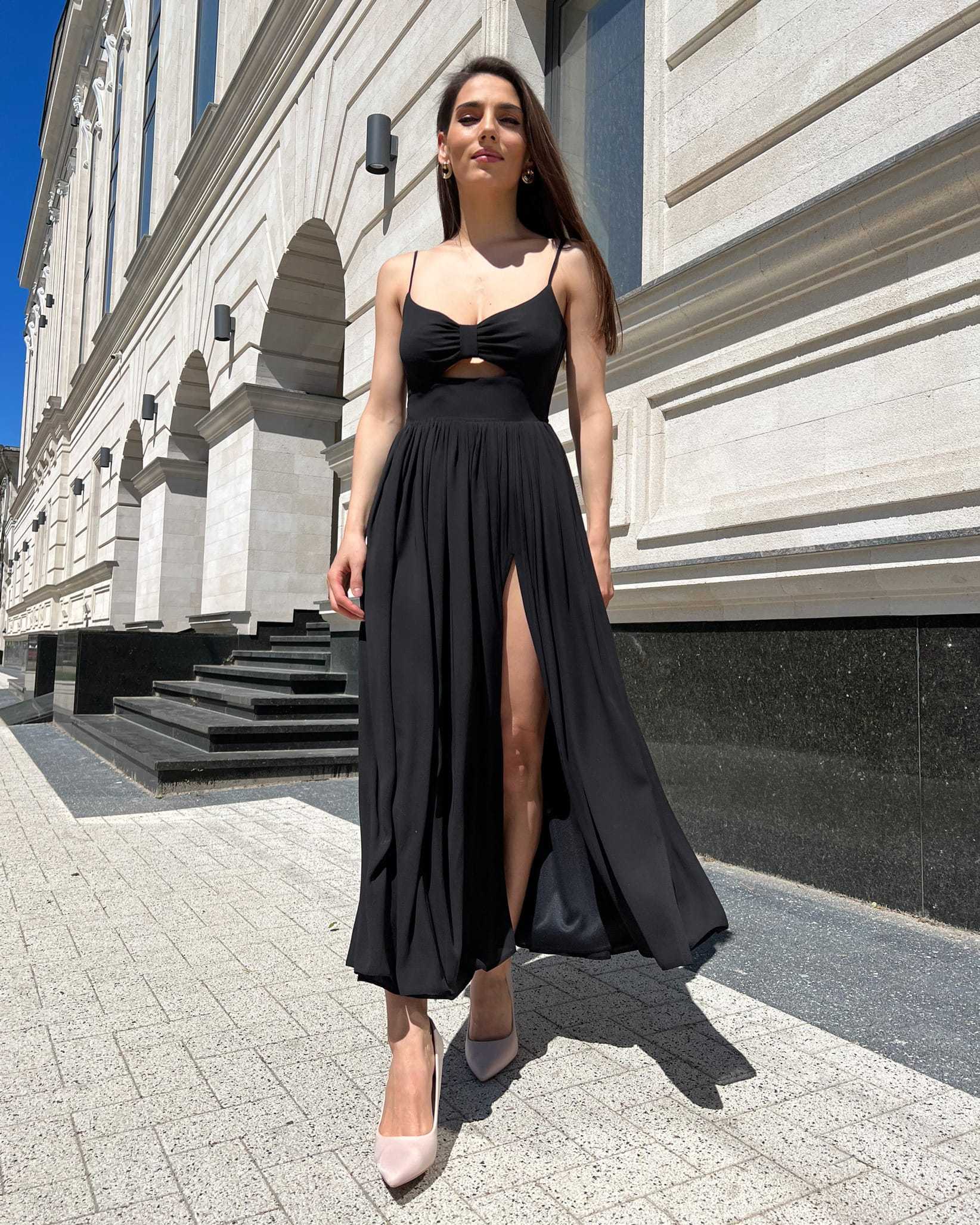 Rochie neagra lungă cu bretele și slit pe piciorul stâng.